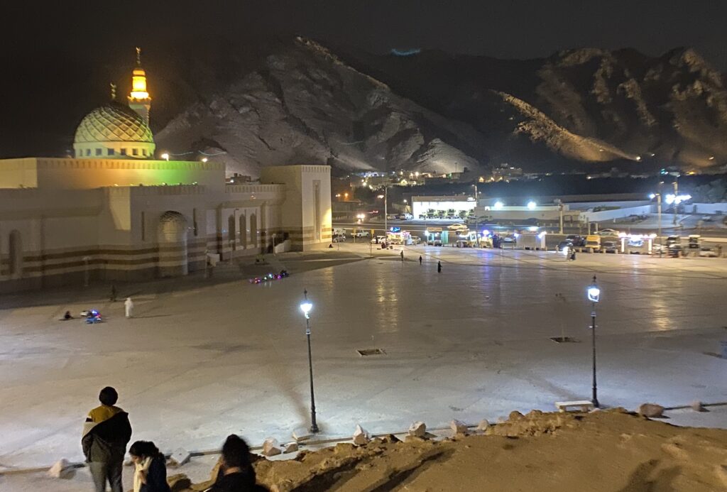 A night view of a mountain behind a lit up mosque