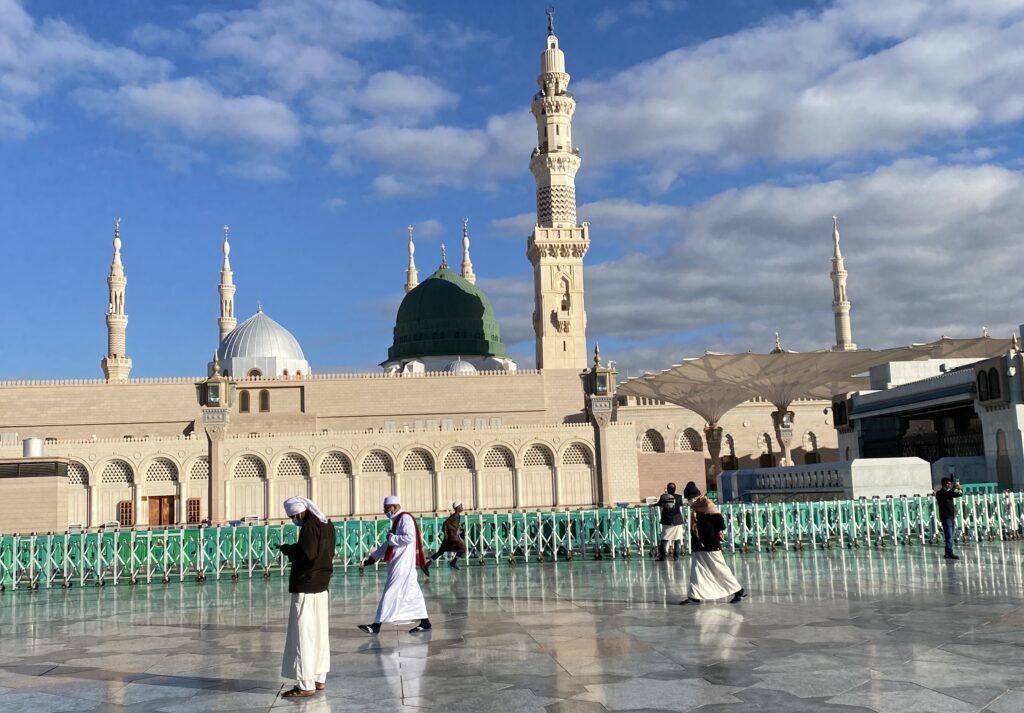 A day view of a mosque with people walking in front of it