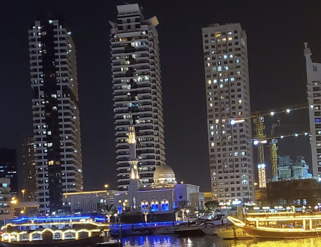 Night time view of tall buildings overlooking a marina filled with boats
