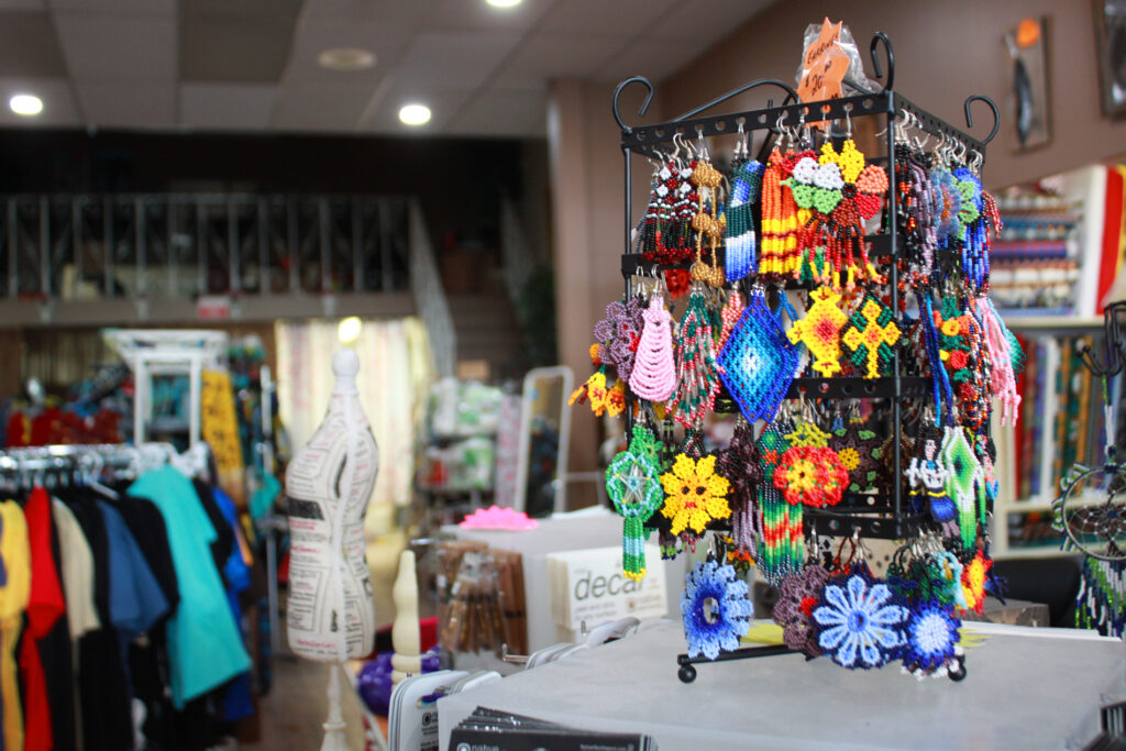A display of beaded earrings, and the dark upper level of the store in the background