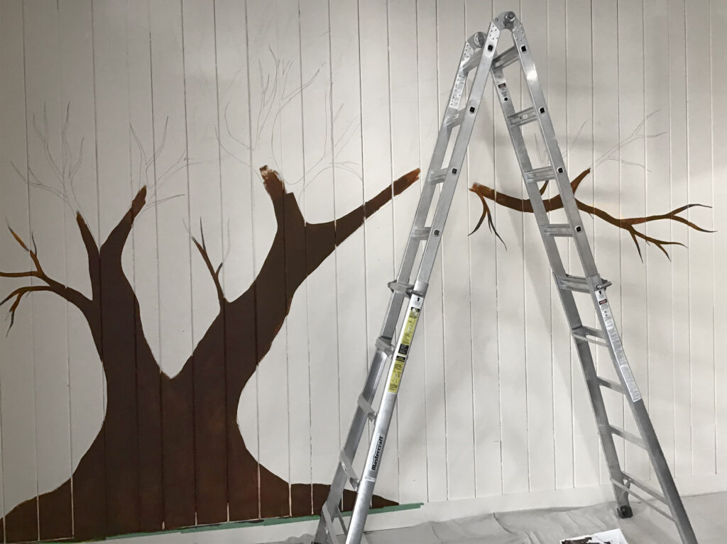 A ladder next to an incomplete mural of a cherry blossom tree