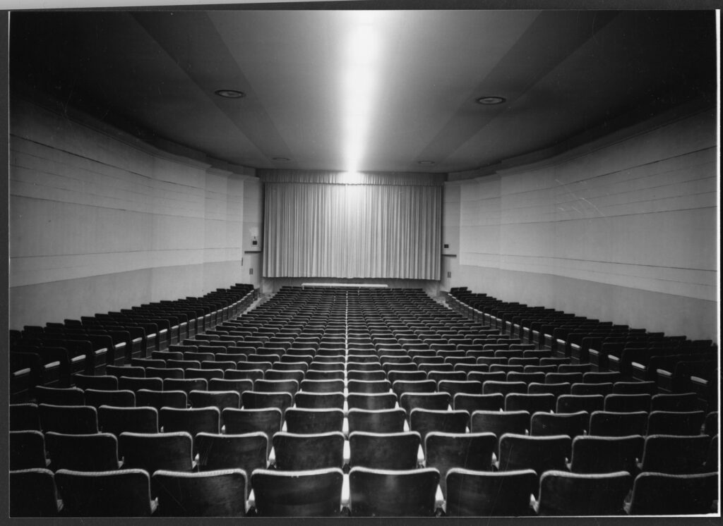 Black and white photo shows an empty Theatre looking towards the screen.